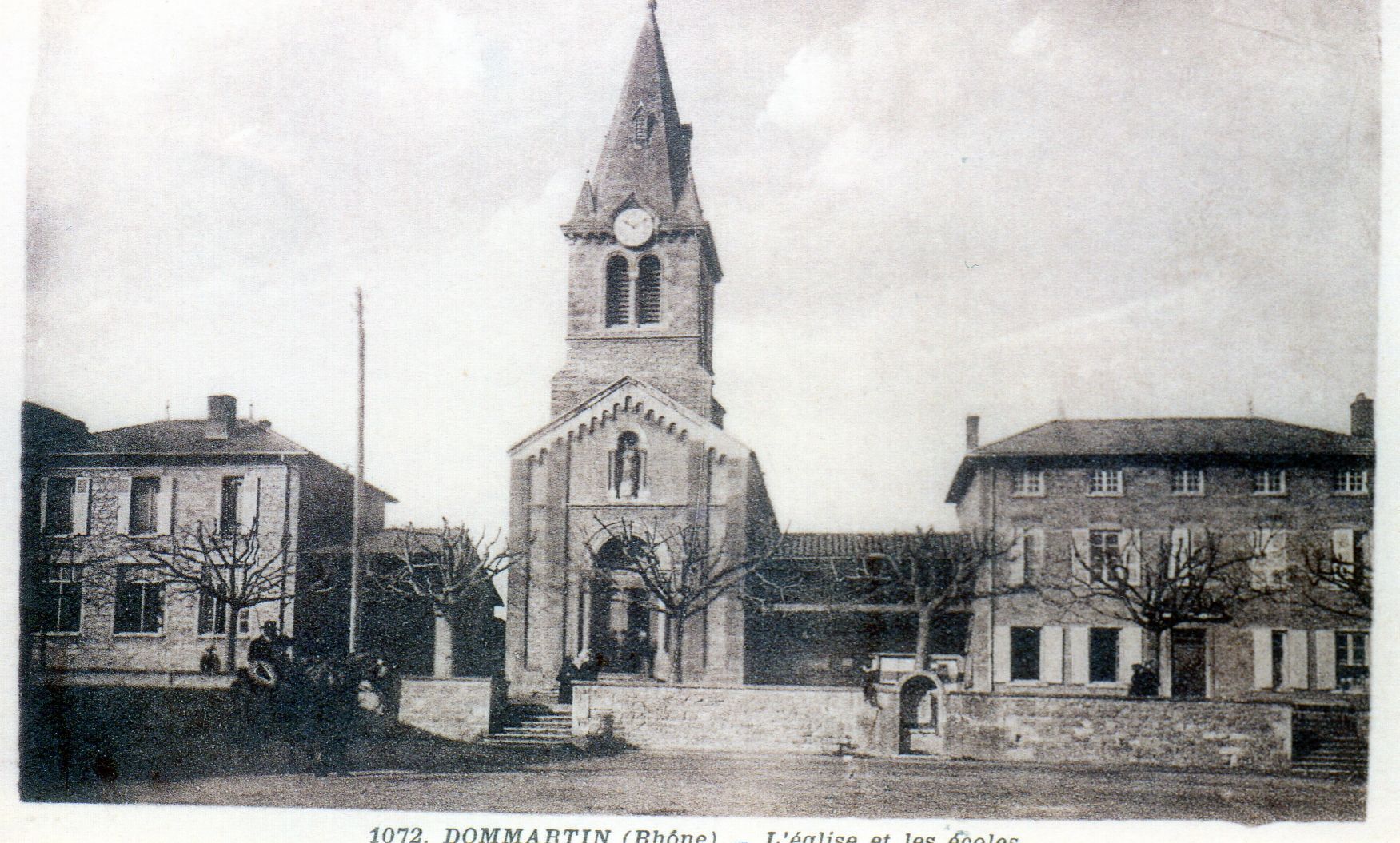 Église au haut clocher flanquée de bâtiments sur une place de village.