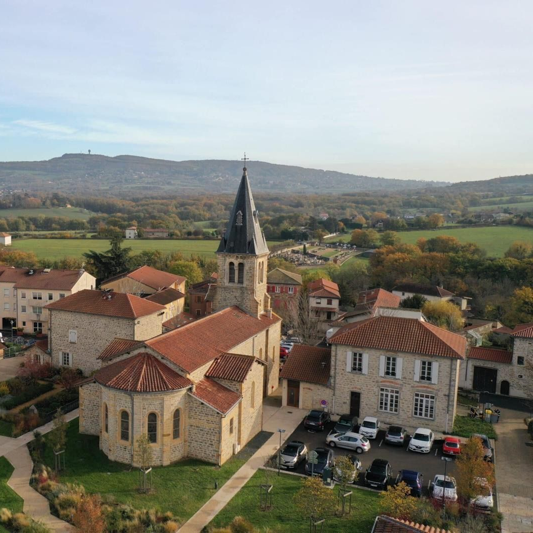 Vue aérienne d'une ville européenne avec une église et les bâtiments environnants par une journée ensoleillée.