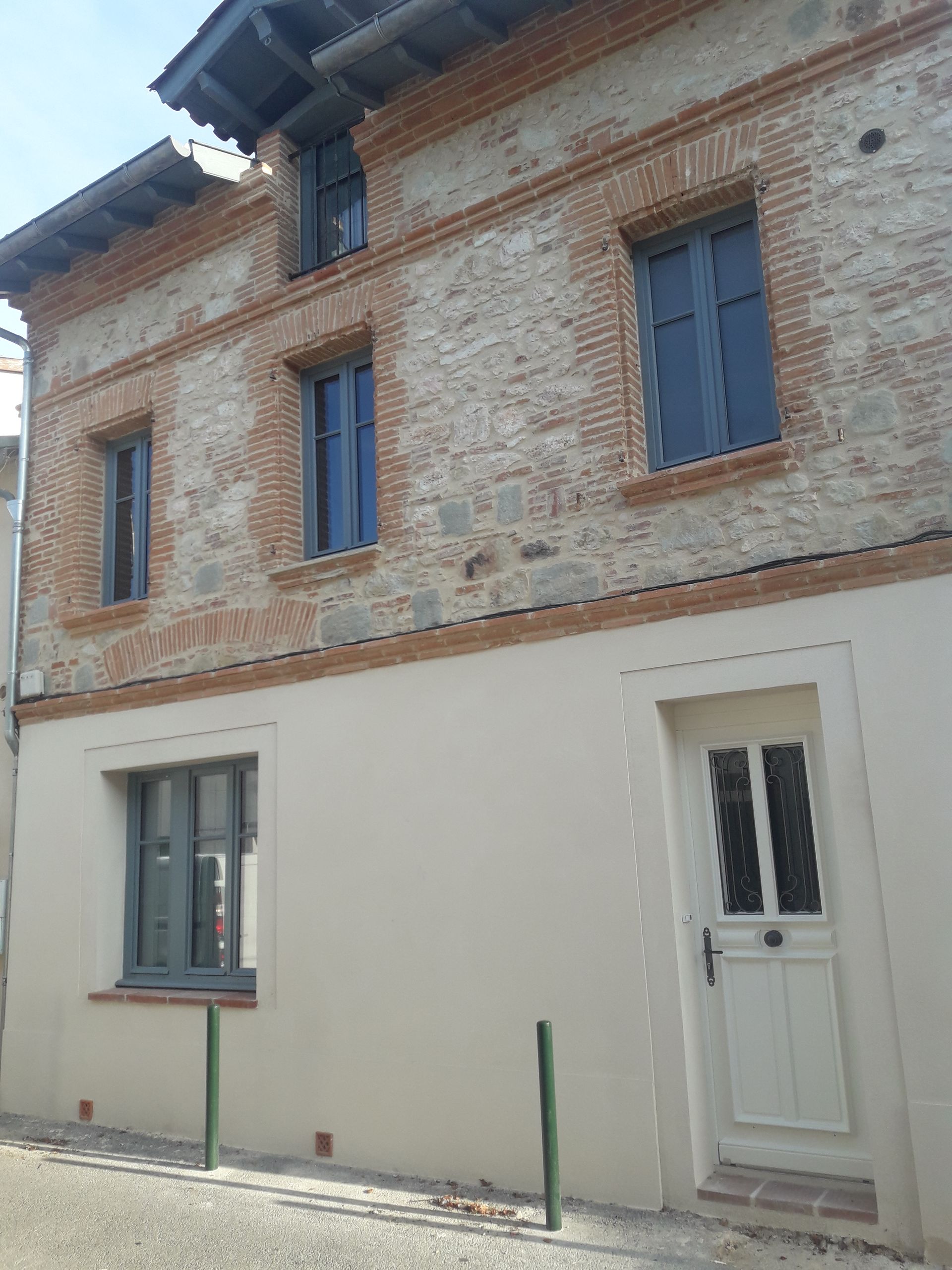 Une façade avec un mur blanc et des pierres apparentes