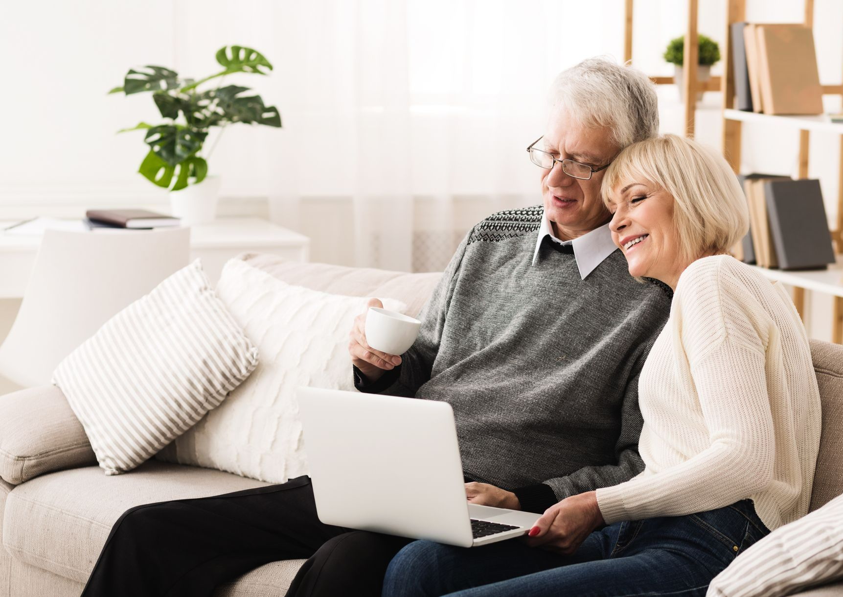 Une femme et un homme devant un ordinateur portable assis sur un canapé