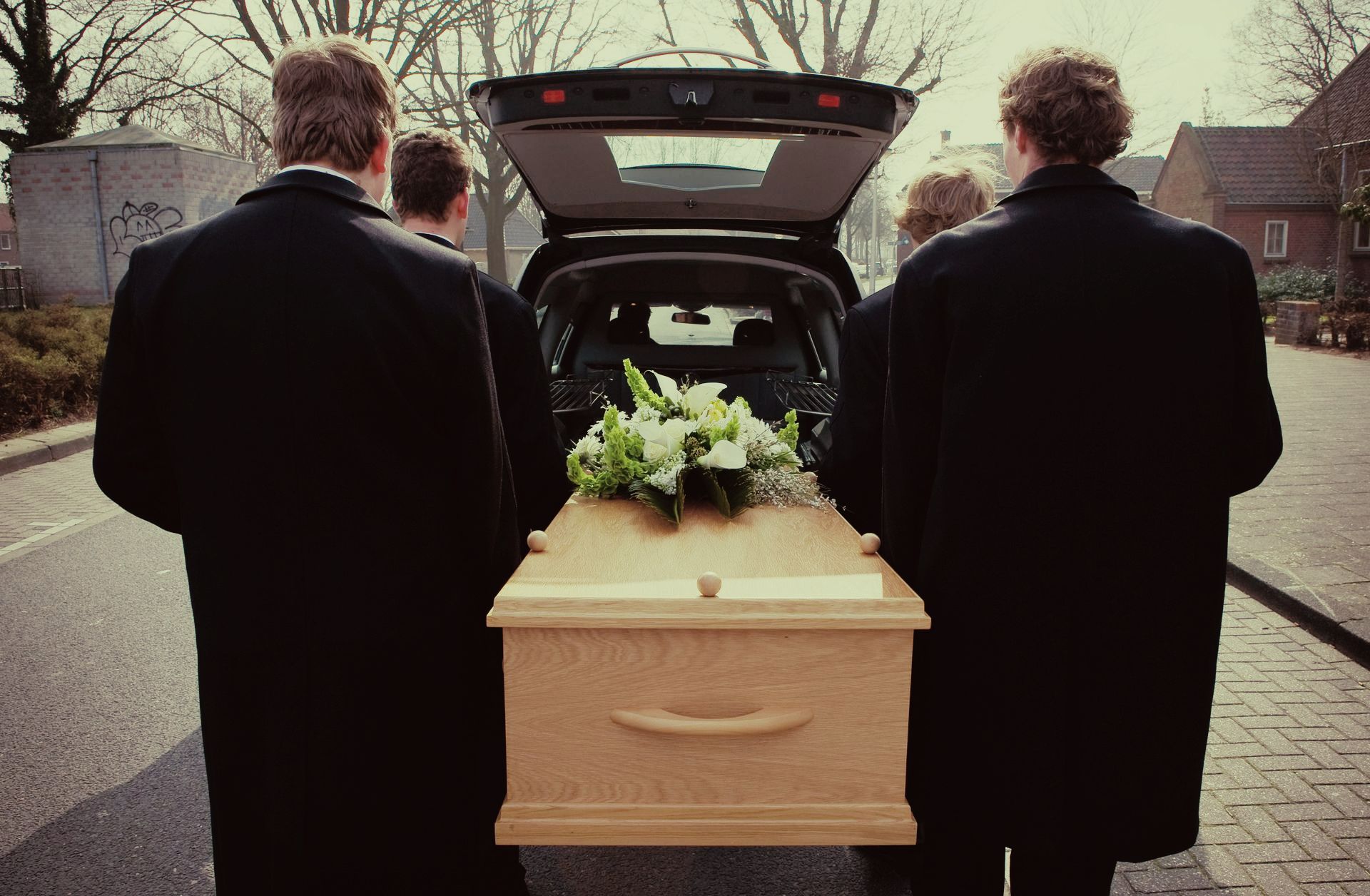 Des personnes tiennent les poignées d'un cercueil