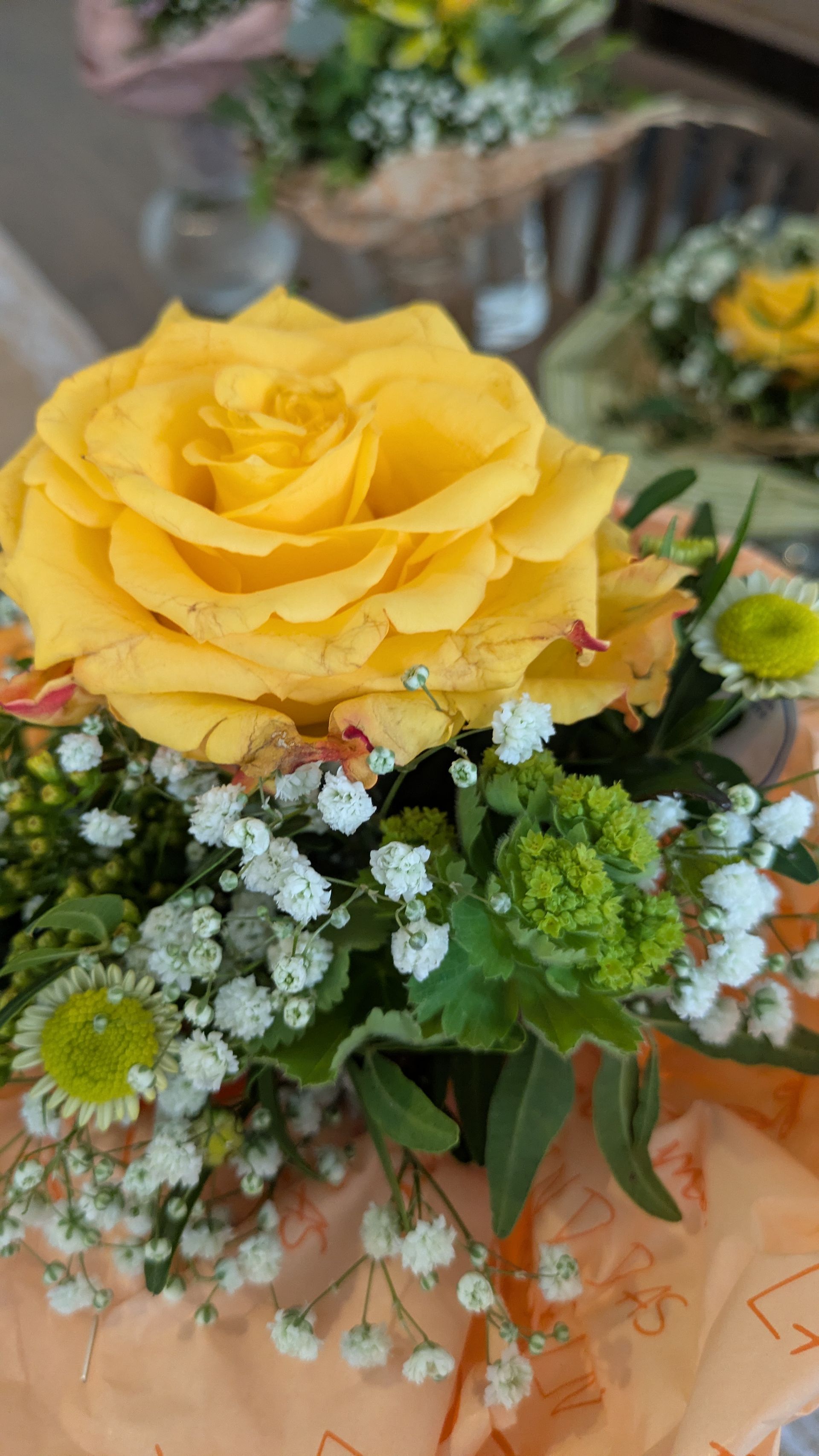 Gelbe Rose in einem Blumenstrauß mit weißen und grünen Füllblumen