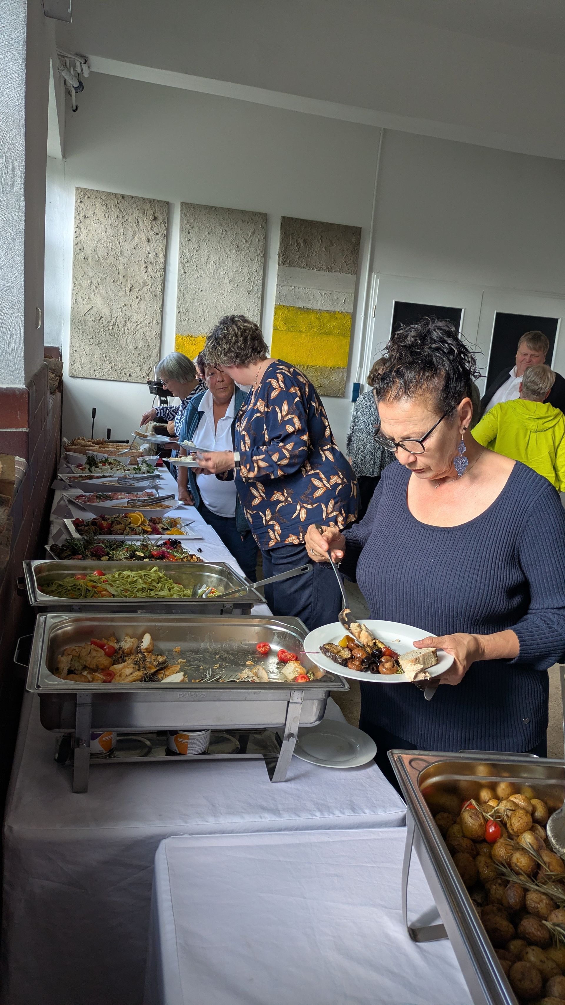 Menschen bedienen sich selbst an einem Buffet in einem hellen Speisesaal