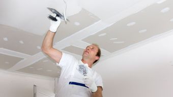 Un homme qui met du plâtre au plafond