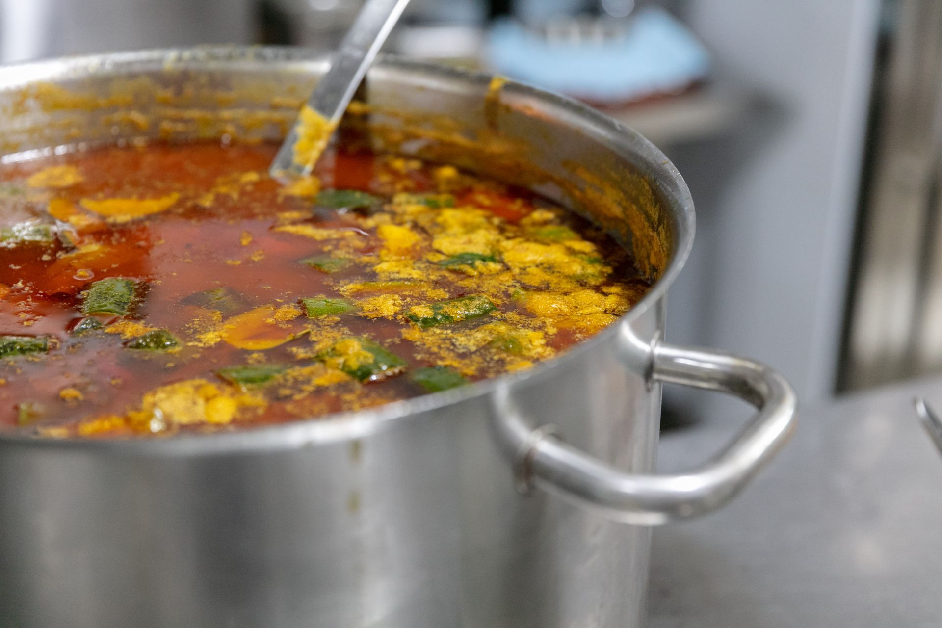 Une marmite de soupe rouge aux herbes et une louche sur le plan de travail de la cuisine