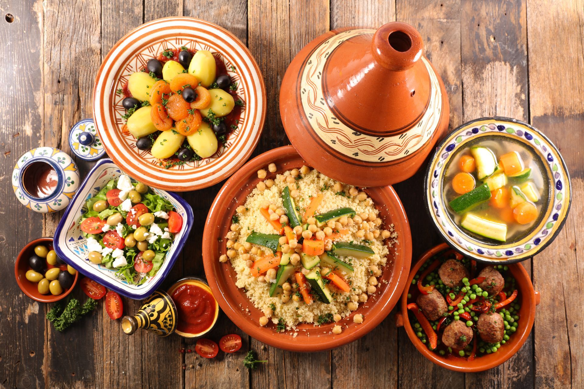 Festin marocain avec des plats colorés, du couscous, des tajines, de la salade et du ragoût sur une table rustique en bois
