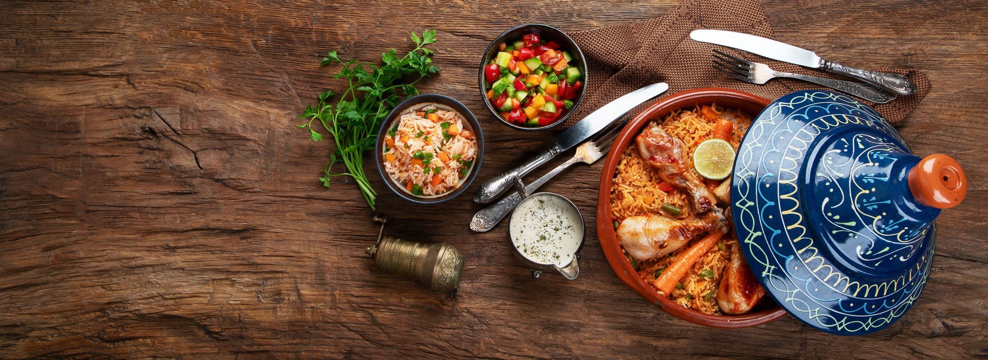 Vue aérienne d'une table rustique avec des bols de soupe, des parts de pizza, des herbes aromatiques et une théière bleue