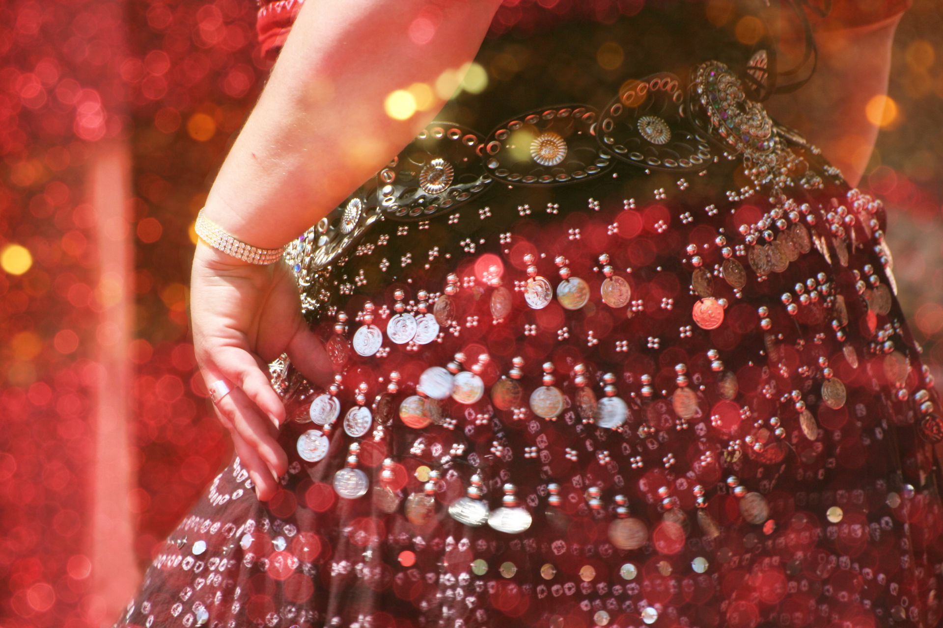 Main posée sur un vêtement rouge à paillettes sur un fond chaud et scintillant