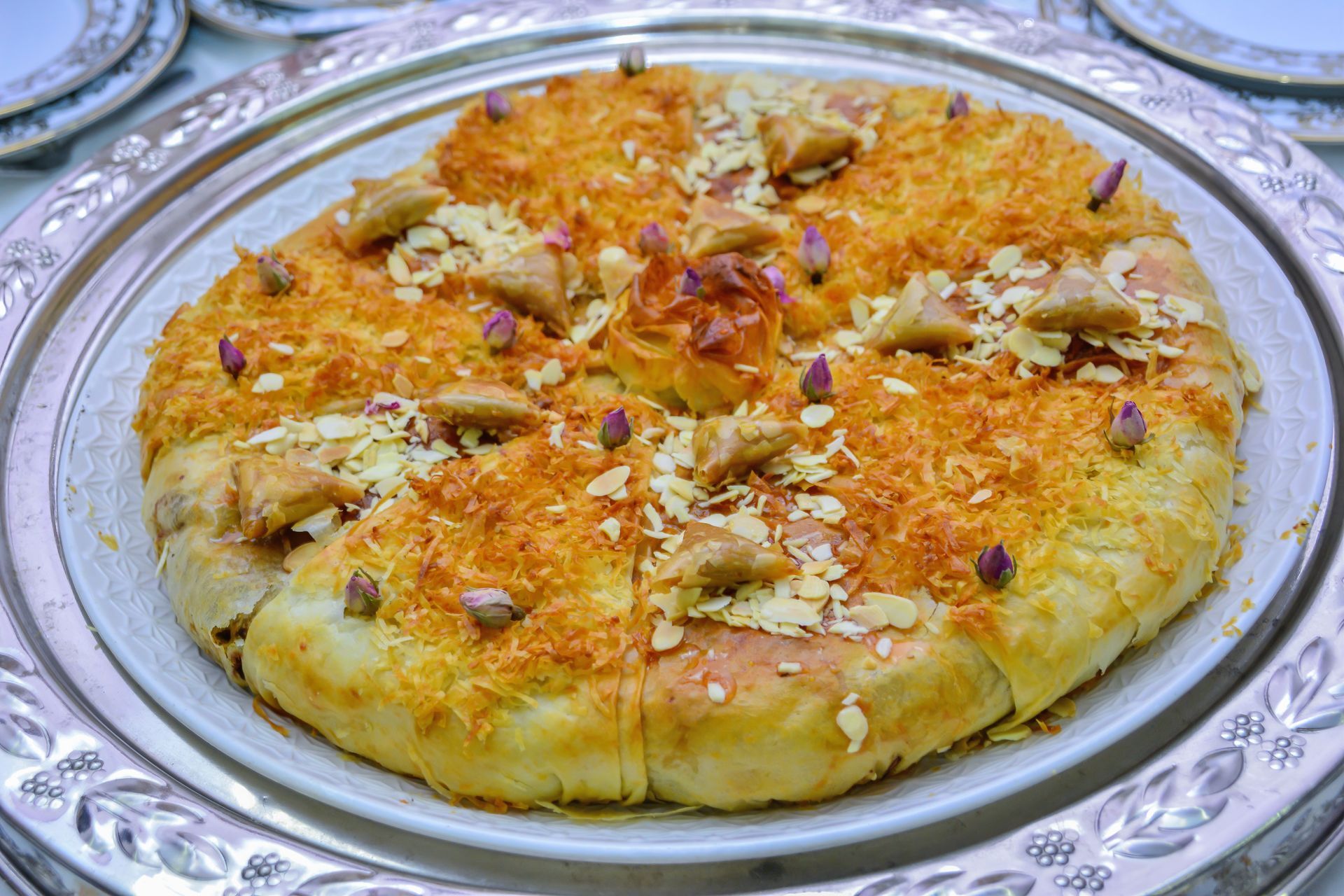 Dessert rond garni de noix doré et coupé en quartiers et présenté sur un plateau argenté.