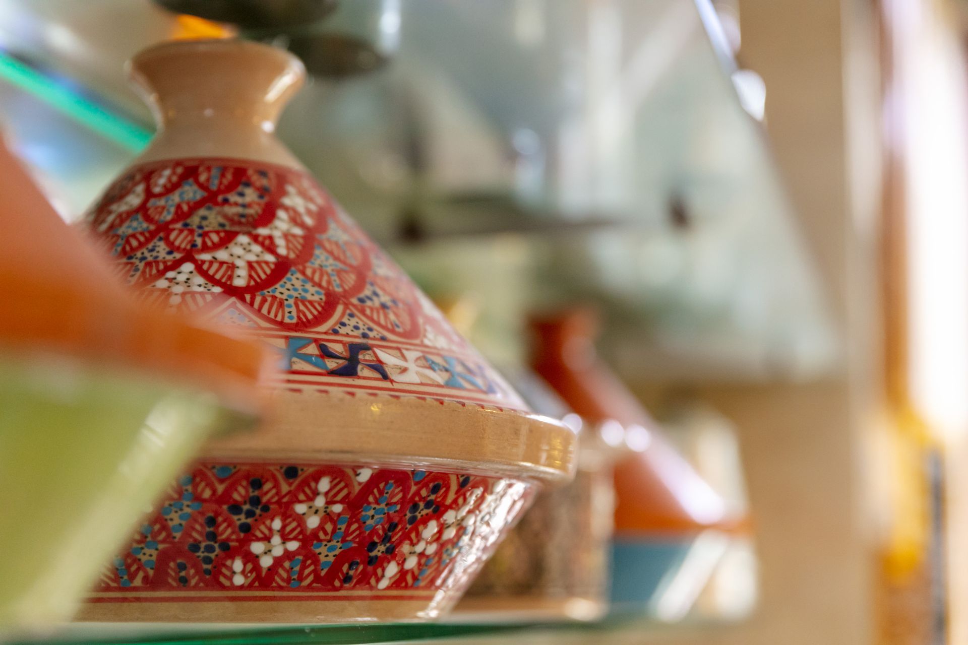 Plat en céramique à motifs rouges et bleus sur une étagère dans une boutique à l'éclairage tamisé