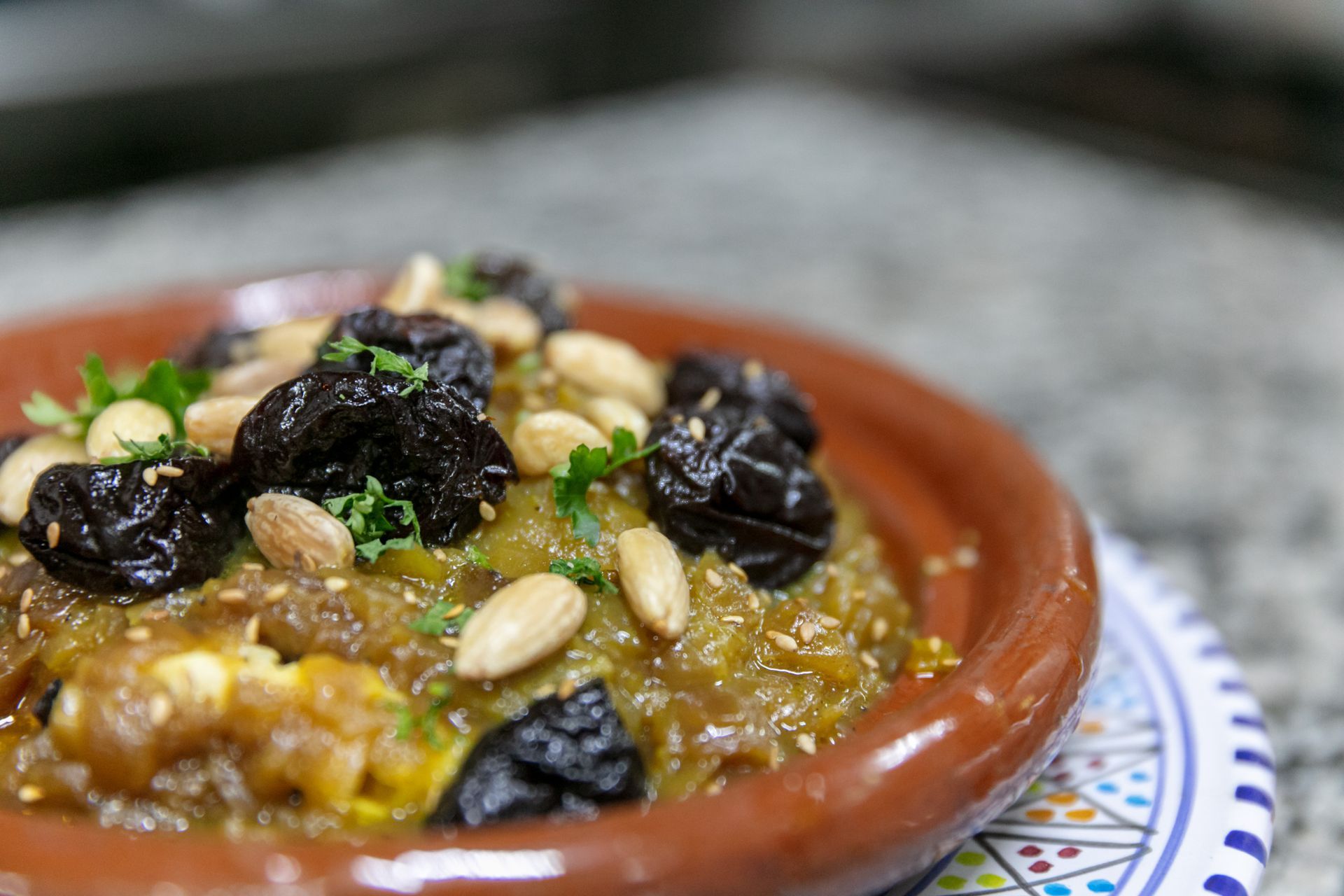 Plat de tajine garni de pruneaux et de pignons de pin dans un bol en terre cuite