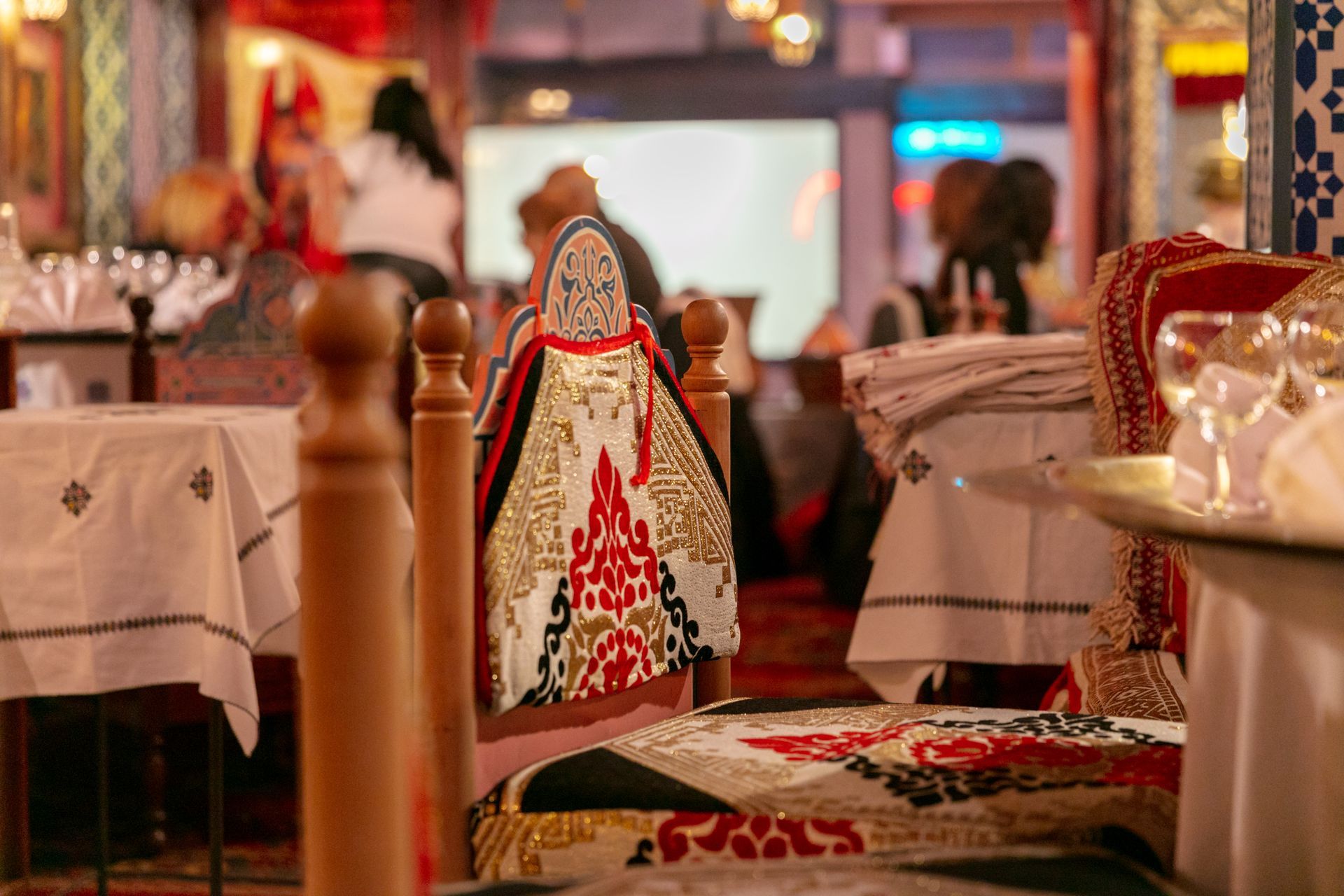 Salle à manger du restaurant avec chaises ornées, nappes blanches et éclairage d'ambiance chaleureux