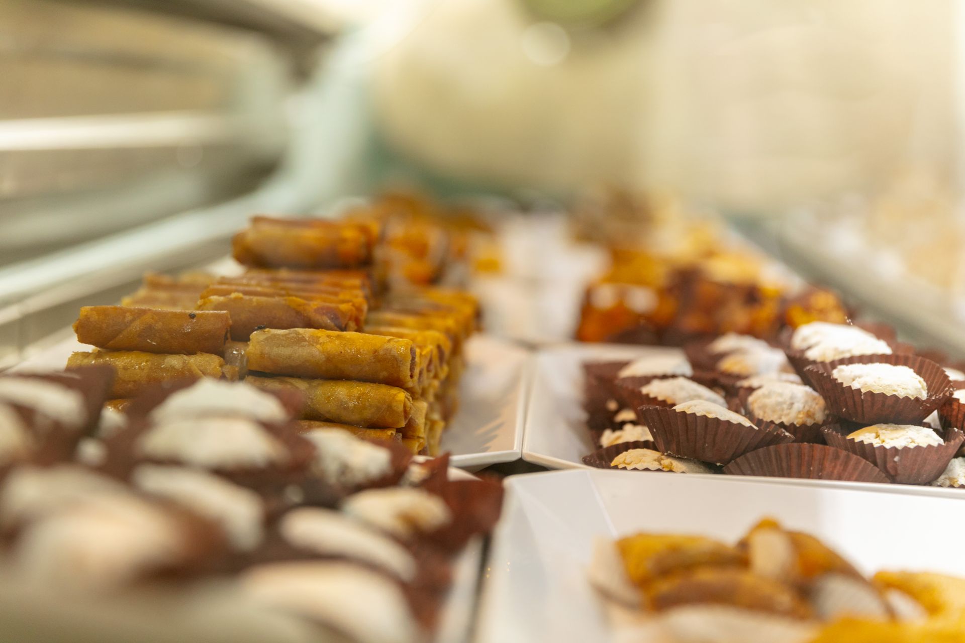 Assortiment de pâtisseries et de biscuits disposés sur des plateaux dans une vitrine de boulangerie.