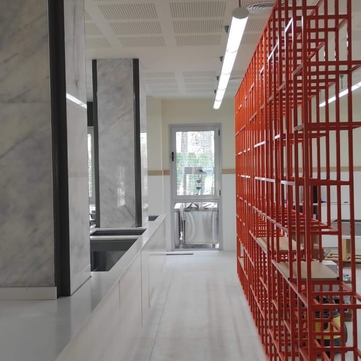 Un largo pasillo con una jaula roja en el medio.