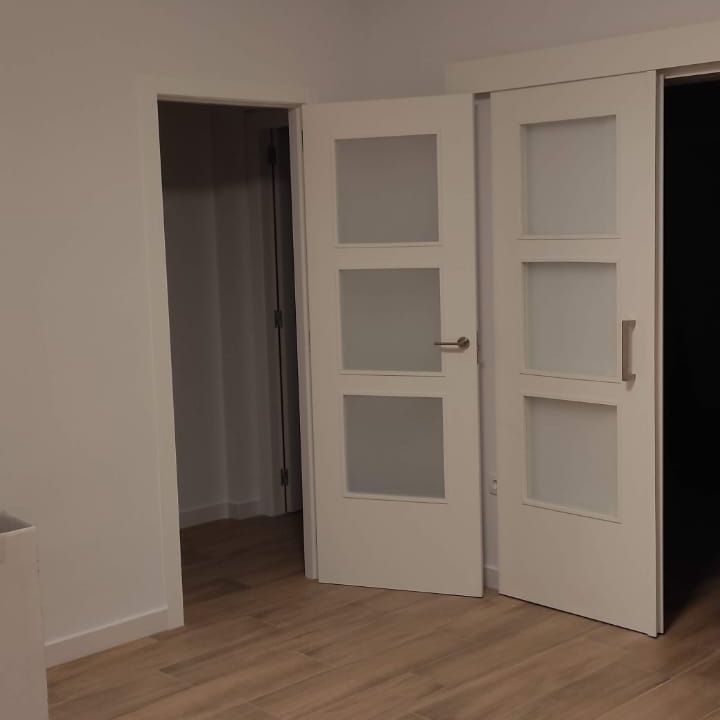 Una habitación vacía con puertas blancas y piso de madera.