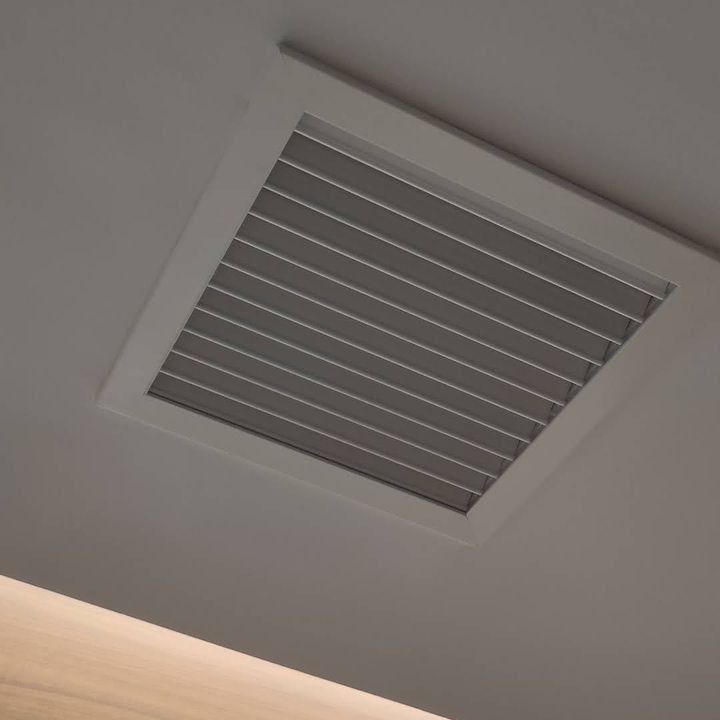 Un respiradero cuadrado cuelga del techo de una habitación.