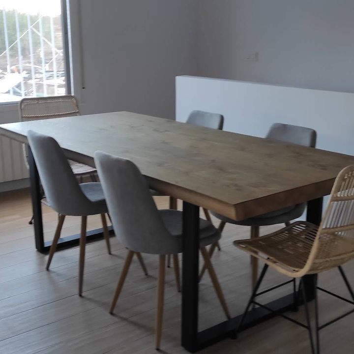 Una mesa y sillas de madera en una habitación con ventana.