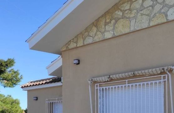 Una casa con una ventana y un muro de piedra