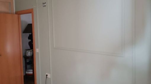 Una pared blanca con una puerta de madera y una lámpara en una habitación.