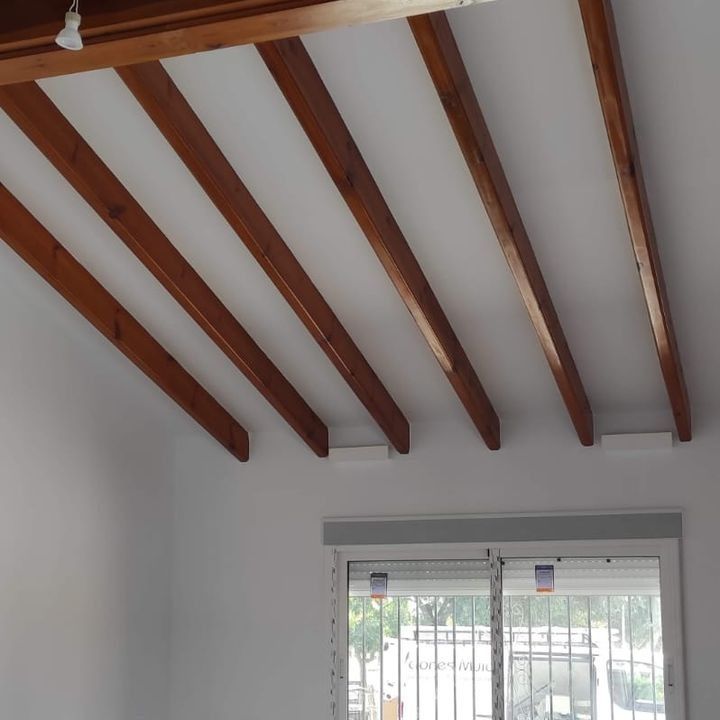 Una habitación con paredes blancas y vigas de madera en el techo.