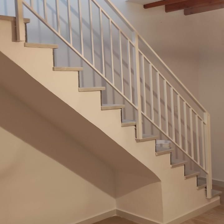 Una escalera blanca con una barandilla blanca en una habitación.