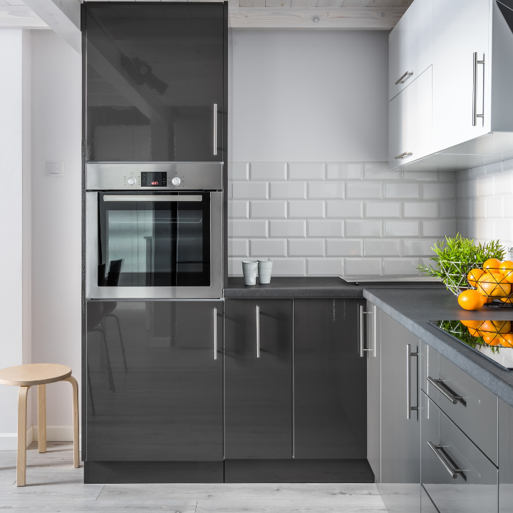 Cocina moderna en color gris y blanco con horno integrado en un mueble alto.