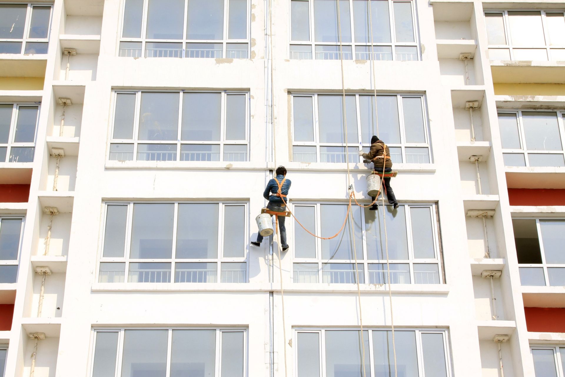 Dos hombres están limpiando las ventanas de un edificio alto.