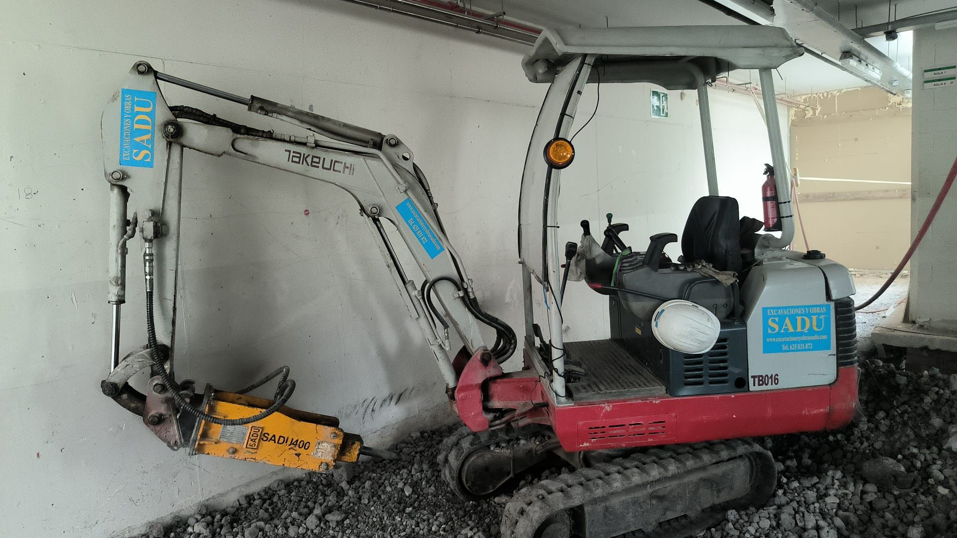 Una pequeña excavadora está estacionada debajo de un puente.