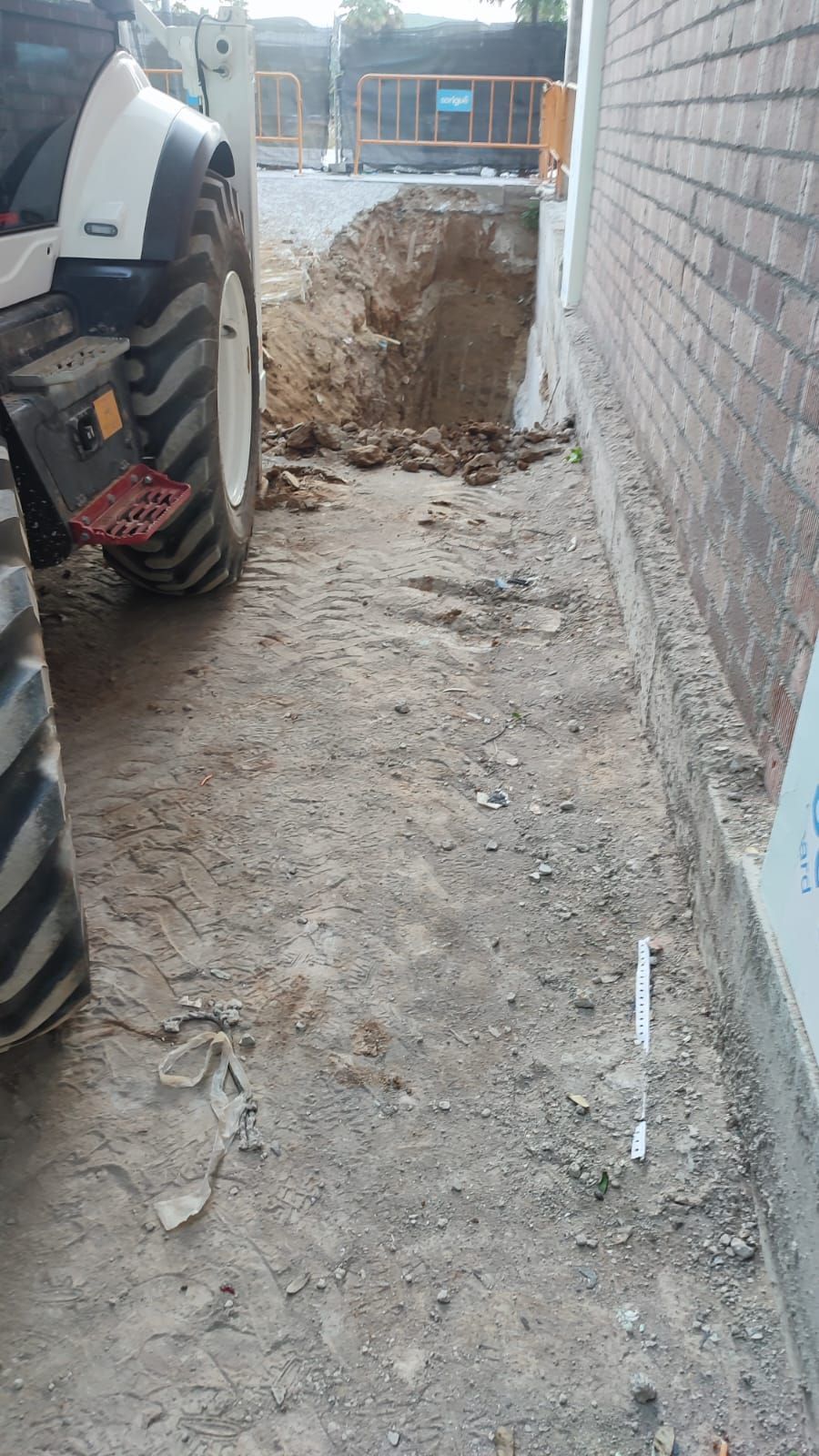 Un tractor está estacionado en un terreno de tierra al lado de una pared de ladrillos.