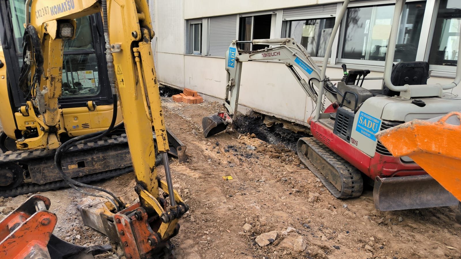 Un grupo de vehículos de construcción están estacionados frente a un edificio.