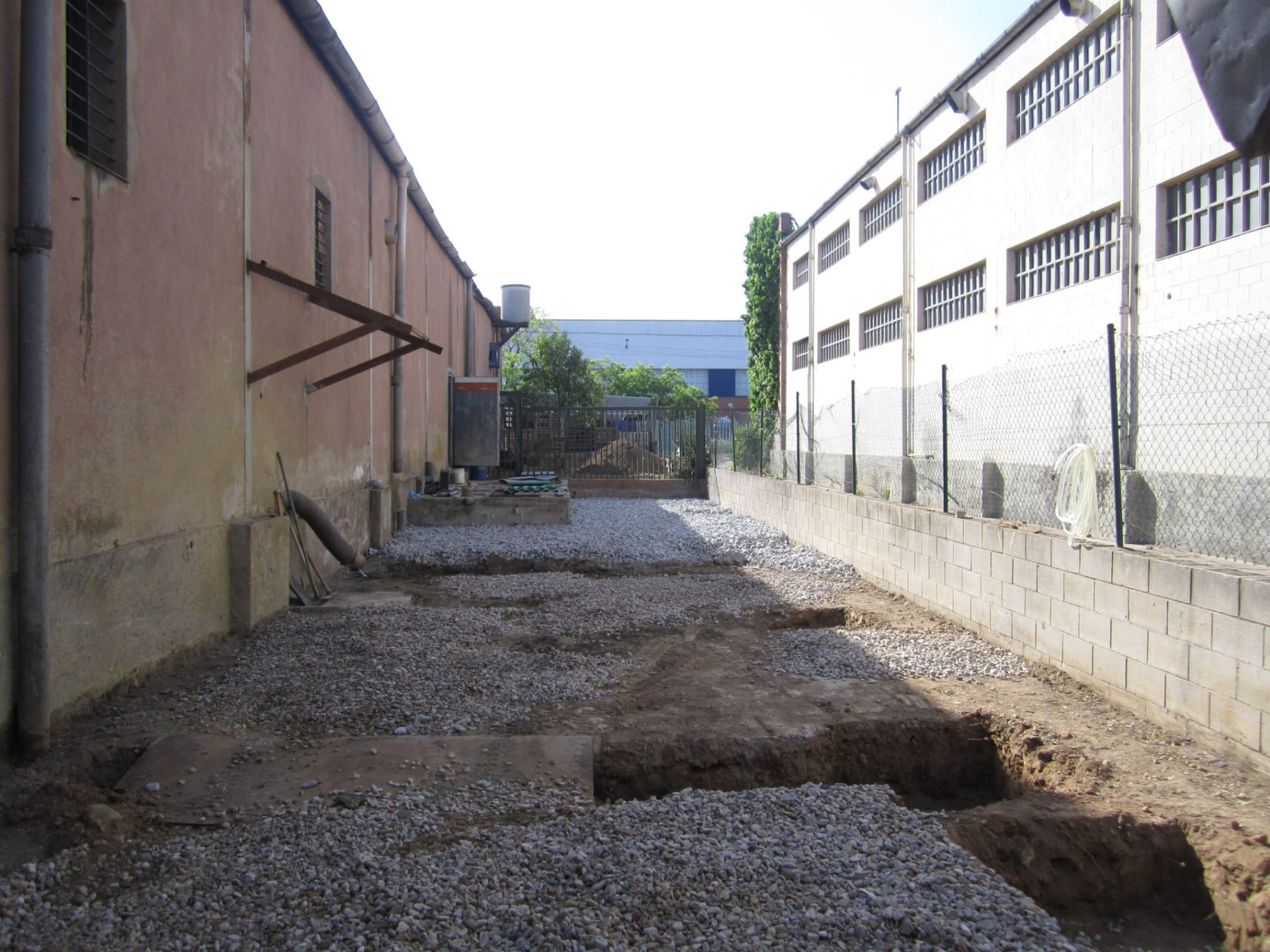 Un edificio con una valla y grava delante.