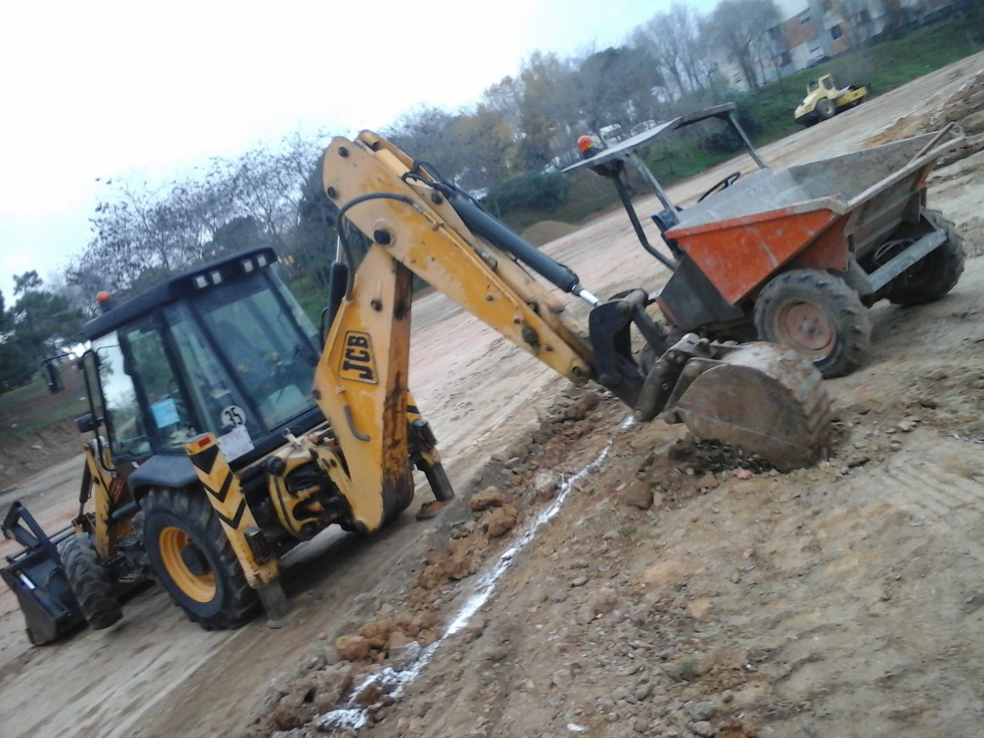 Una retroexcavadora JCB amarilla está cavando en la tierra.