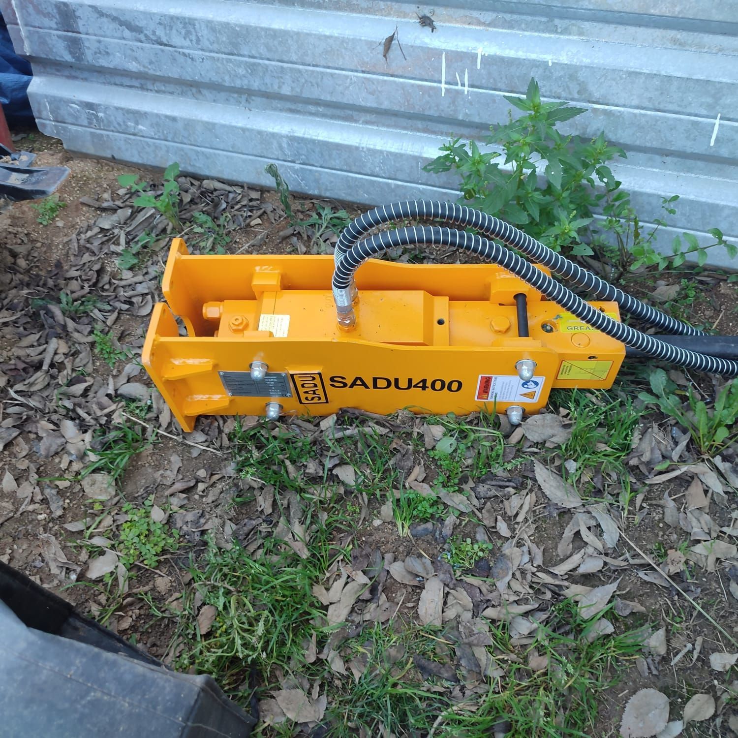 Un martillo hidráulico amarillo está en el suelo.