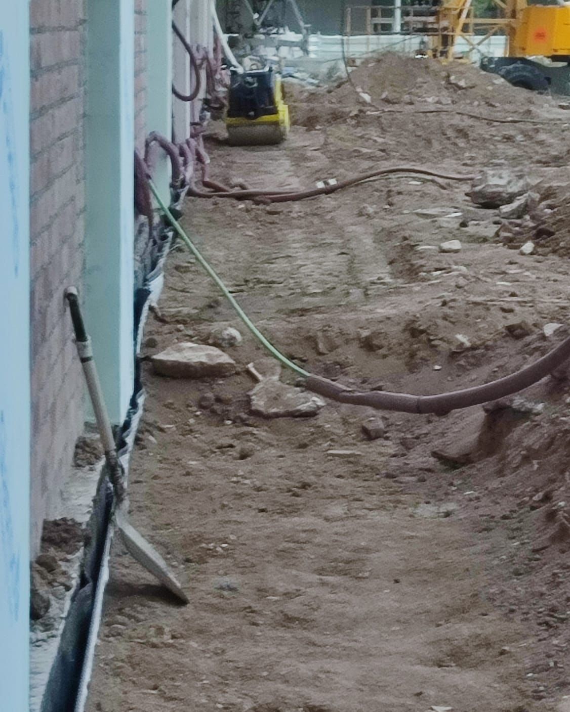 Un sitio de construcción con una manguera conectada al costado de un edificio.