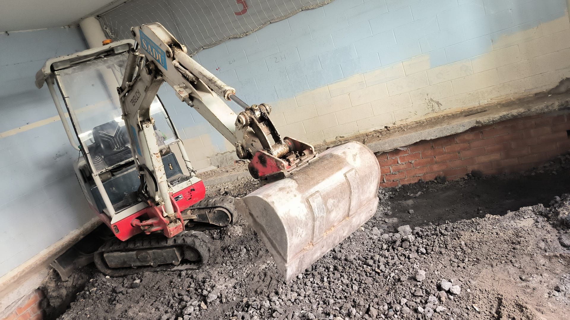 Una pequeña excavadora está cavando un hoyo en el suelo.