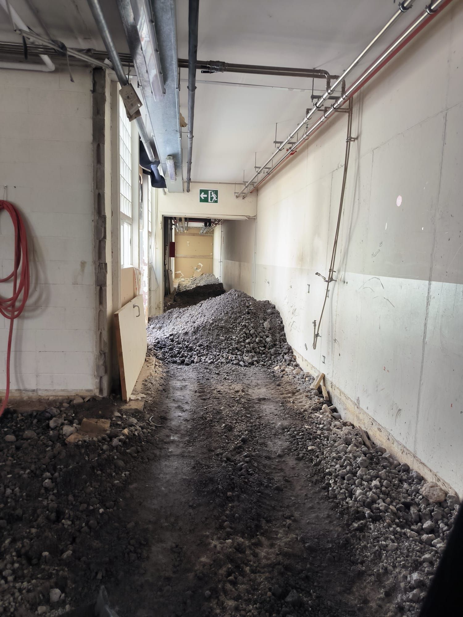 Un pasillo con una manguera roja colgada en la pared.