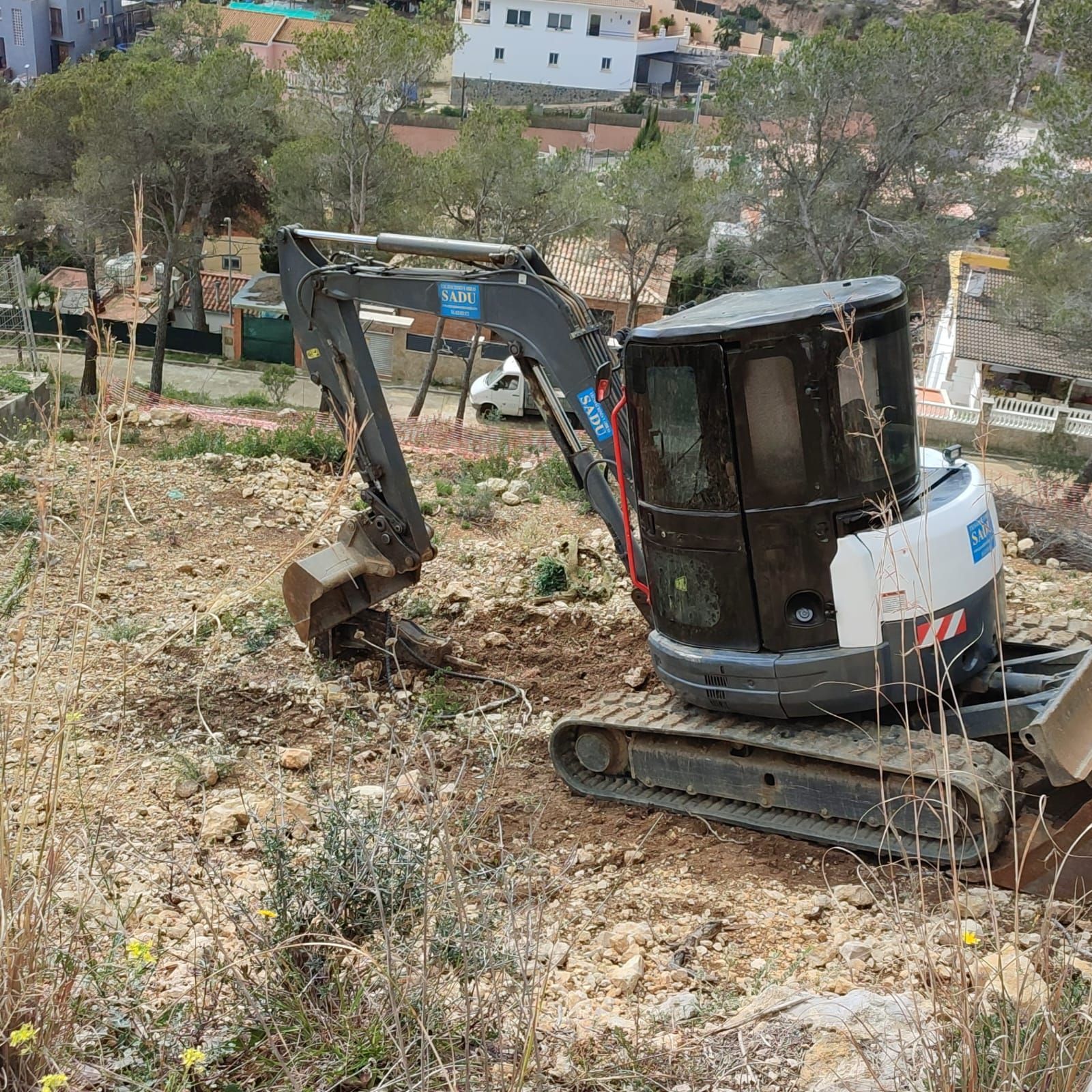 Una pequeña excavadora está en la cima de una colina de tierra.