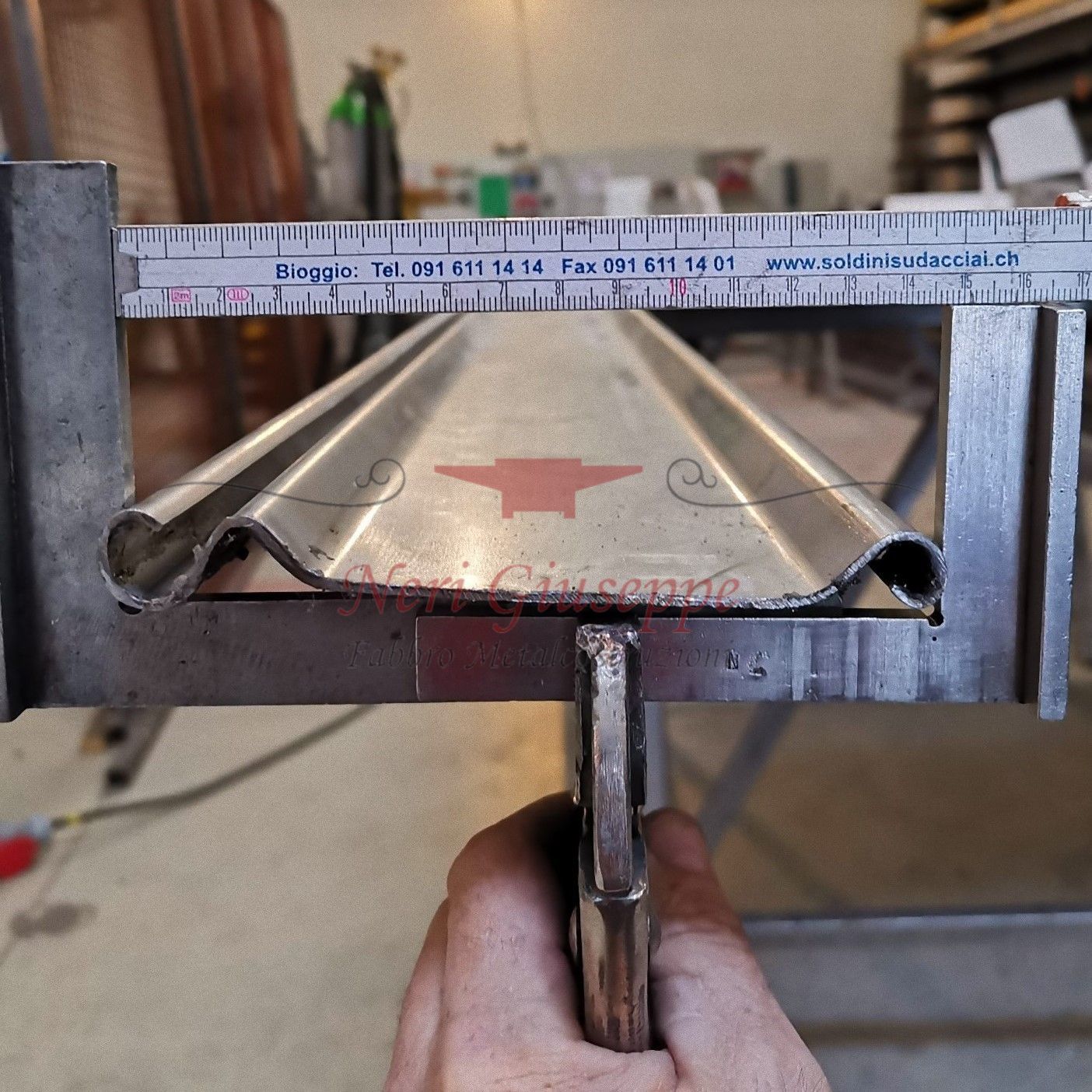 Un uomo sta saldando un pezzo di metallo con una saldatrice.