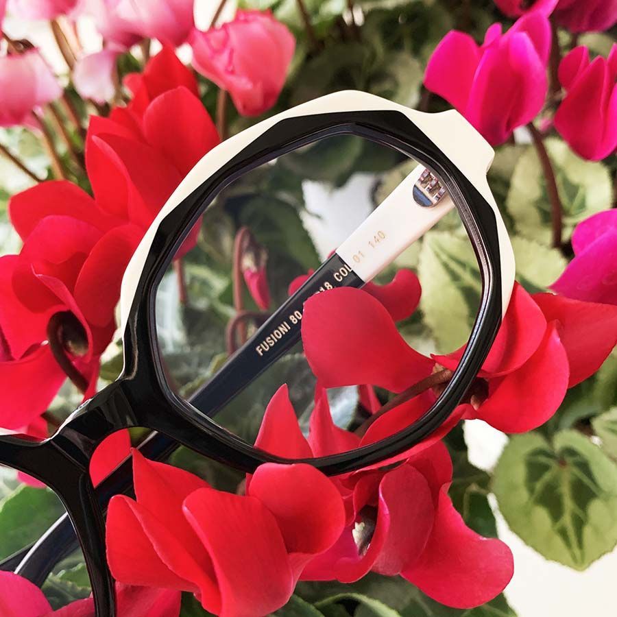 Un par de gafas sobre un ramo de flores rojas.