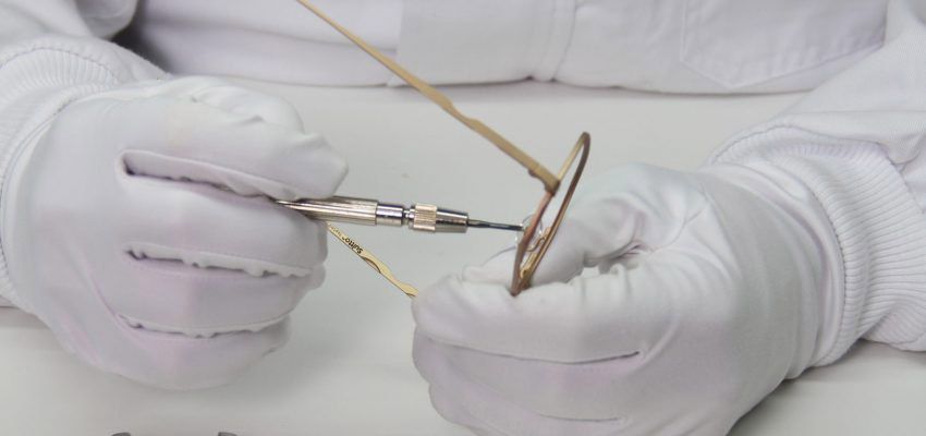 Una persona que lleva guantes blancos está arreglando un par de gafas.