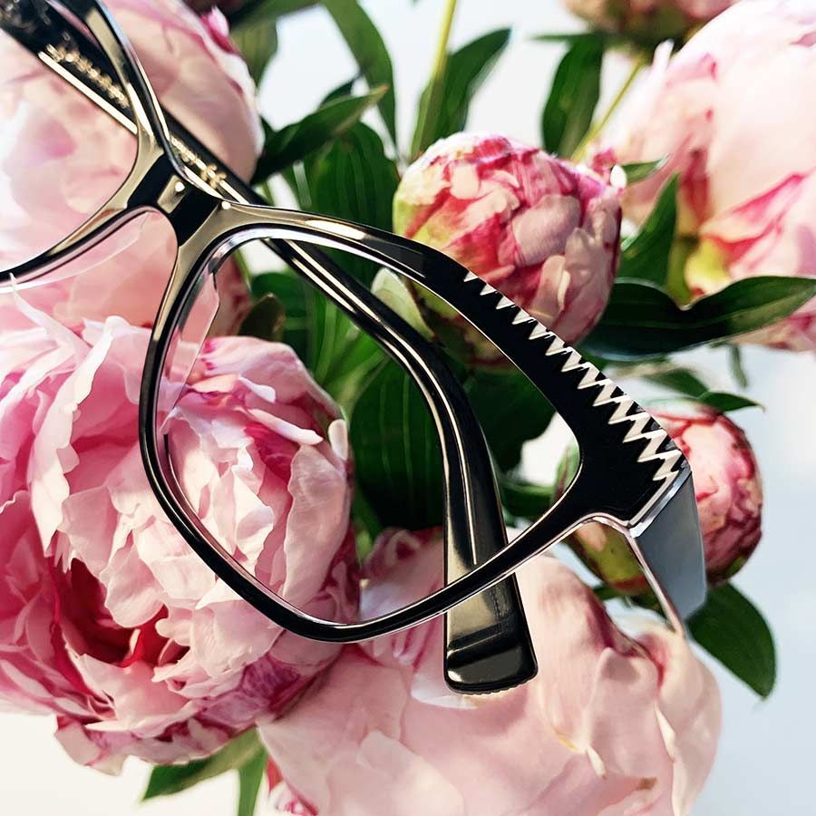 Un par de gafas sobre un ramo de flores rosas.