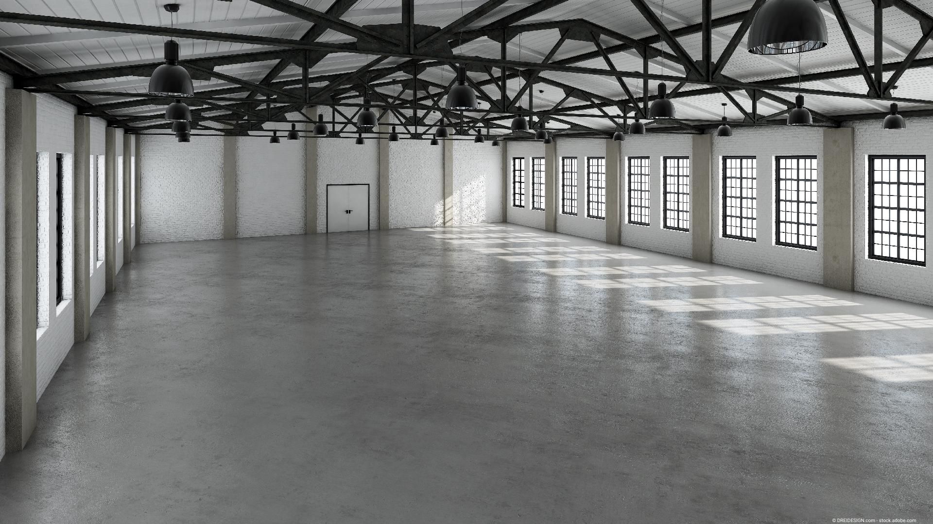 Große Industriehalle mit frisch geglättetem Betonboden, gleichmäßig glänzende Oberfläche.