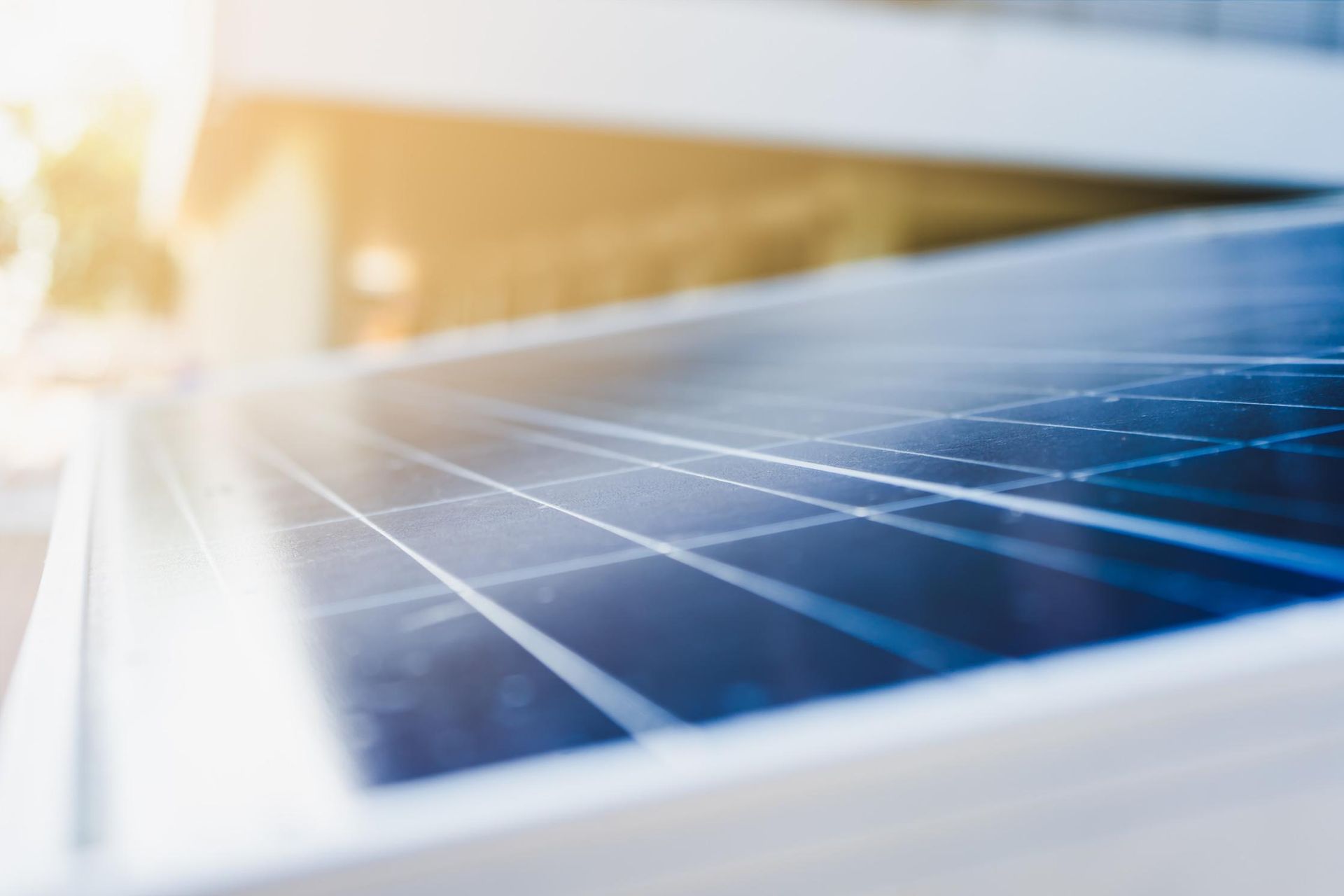 Primer plano de un panel solar con un patrón de cuadrícula, en ángulo con la luz del sol en el fondo.