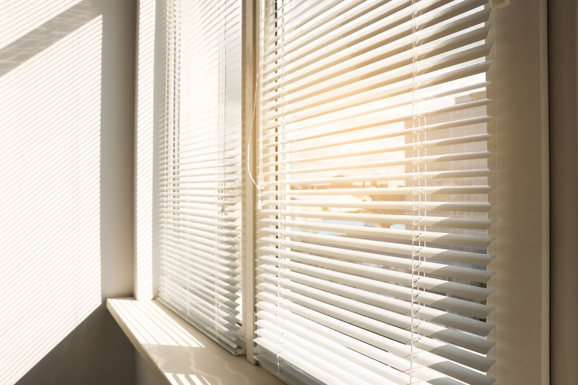 El sol brilla a través de las persianas de una ventana.