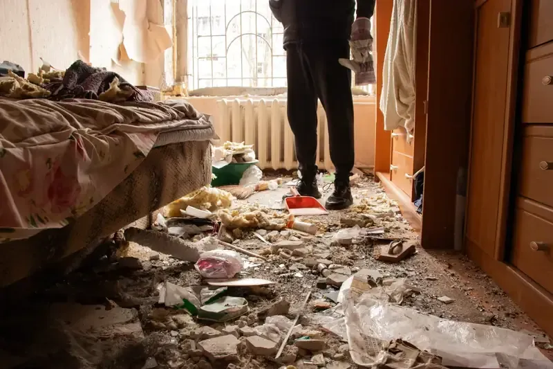 Persona en una habitación con escombros en el suelo, posiblemente de una explosión.