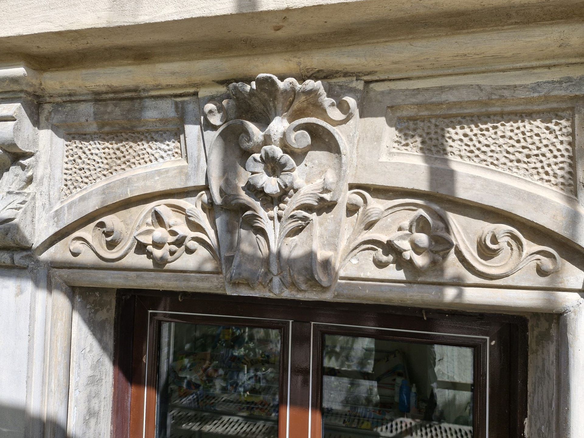 Marco de puerta de piedra ornamentado con tallas florales y friso con motivos.