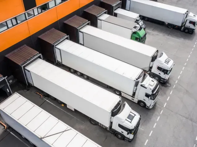 Semi-trucks backed up to a loading dock at a warehouse, ready for unloading.