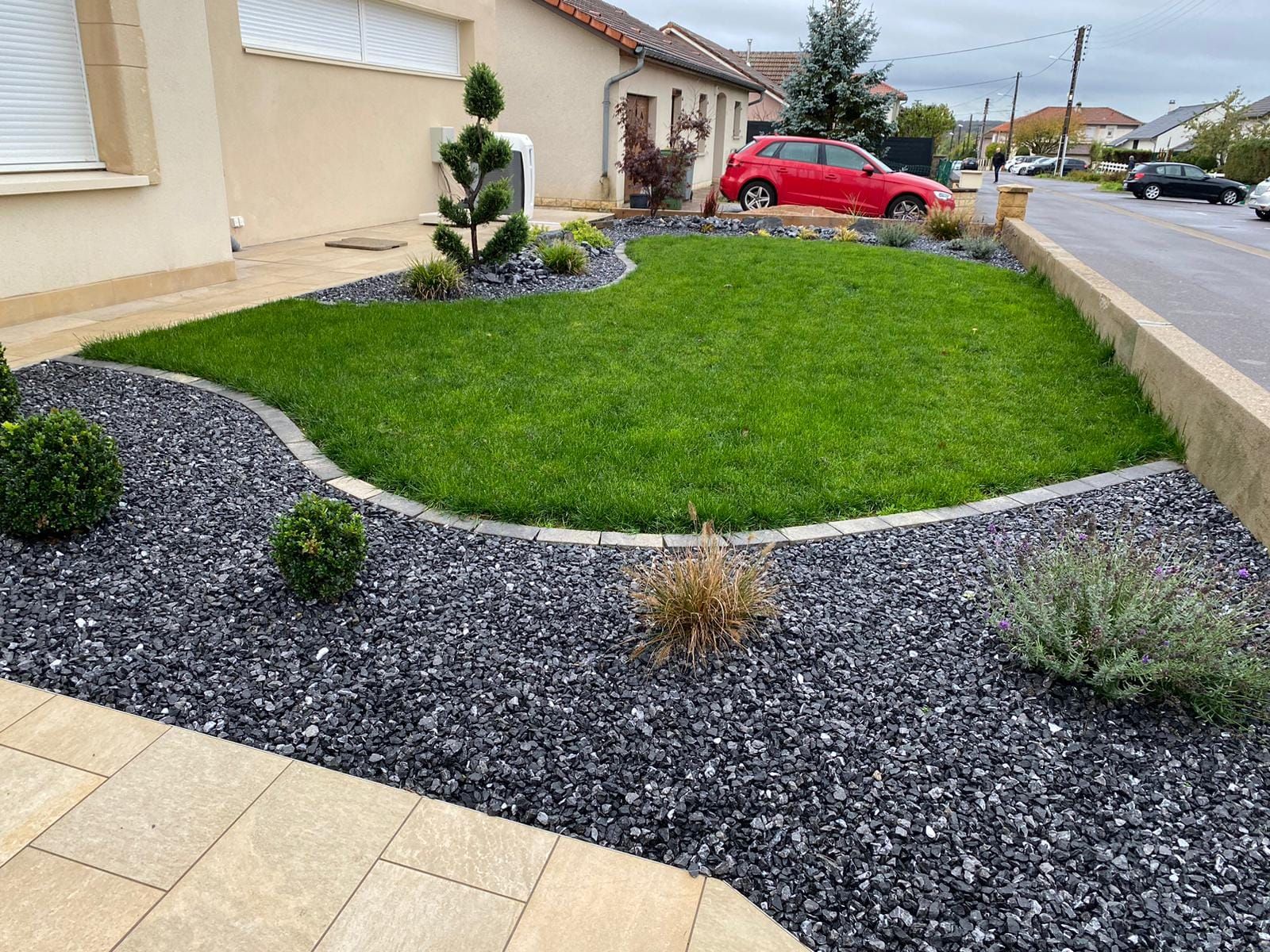 Petit jardin de gazon avec des massifs en pierres noires