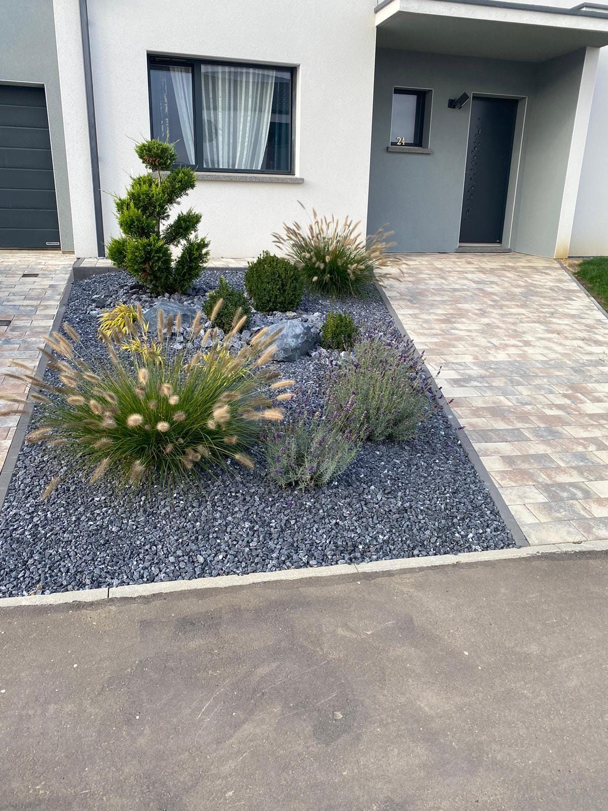 Massif de plantes avec des galets noirs sur une terrasse