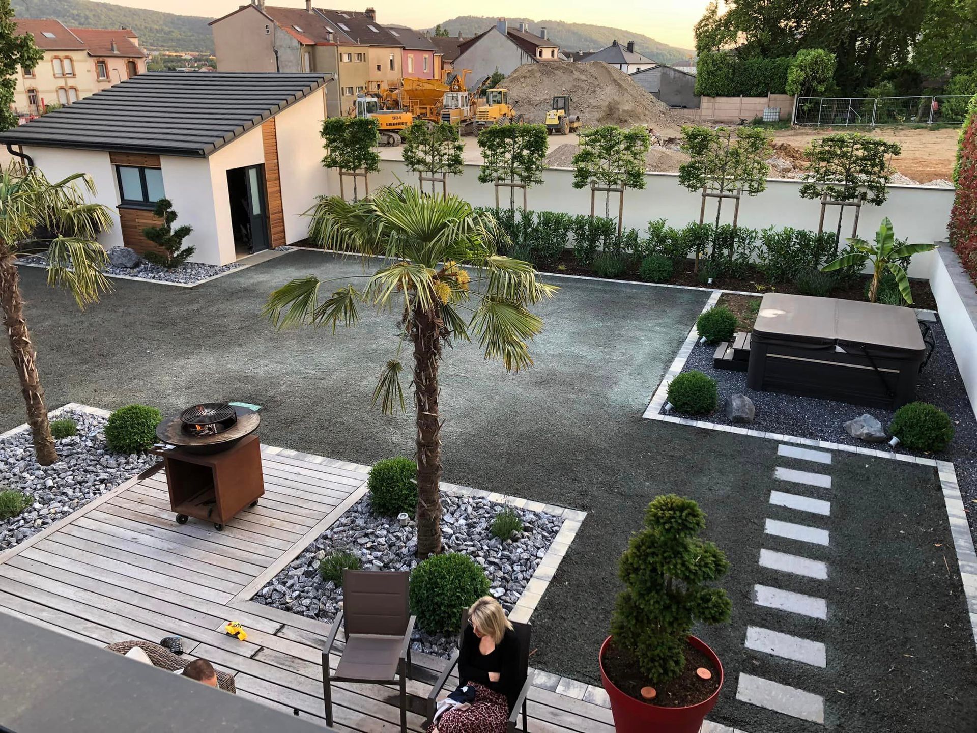 Jardin goudronné entouré de plusieurs massifs de plantes avec un sol en galets